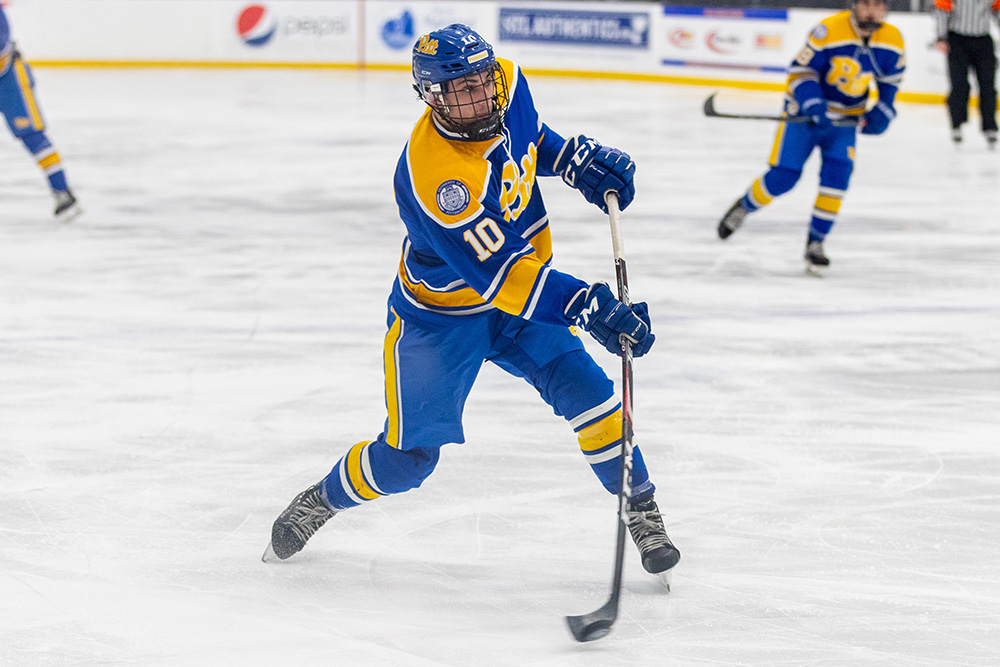 Leslie hits a puck while playing in Pitt ice hockey gear