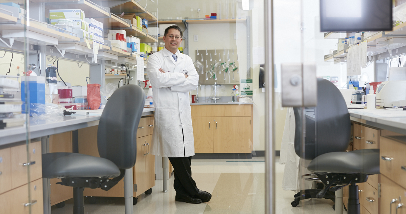 A man in a white lab coat standing in a lab