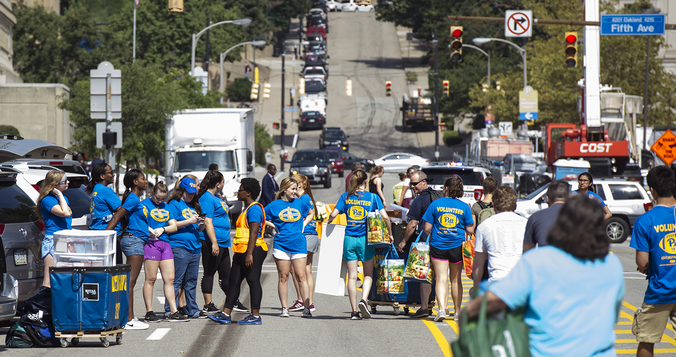 Large group of students in Pitt T-shirts gathered on streets closed to traffic for move-in day on the Pittsburgh campus 