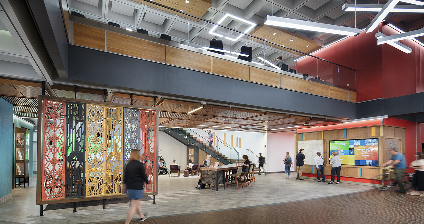 Overall view of the first floor of the Pitt Global Hub, showing colorful furnishings and people walking and sitting in the area