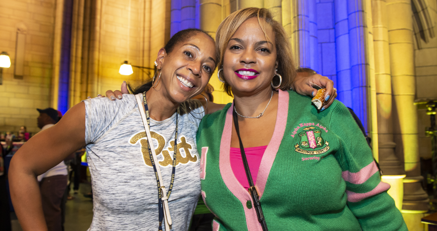 two women with arms around each other smiling, wearing college gear