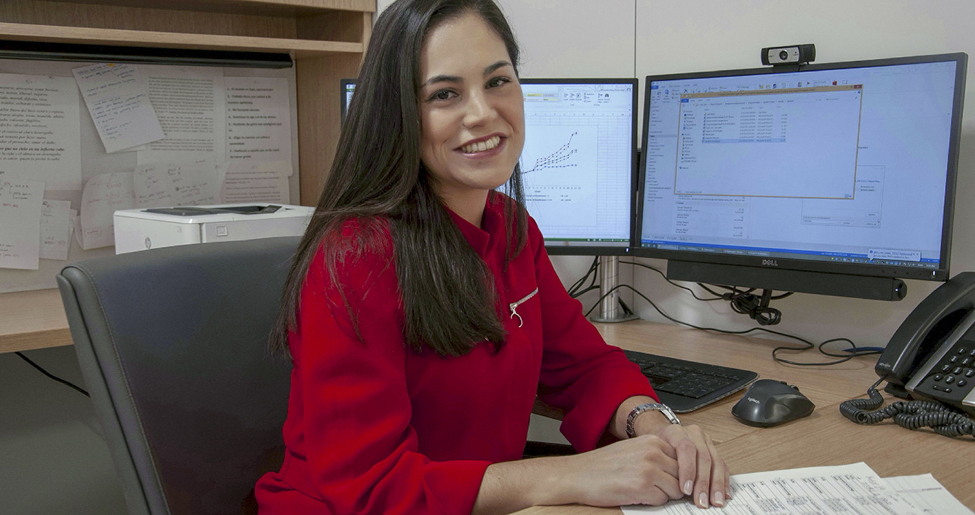 Hernandez in a red blouse in front of computer monitors