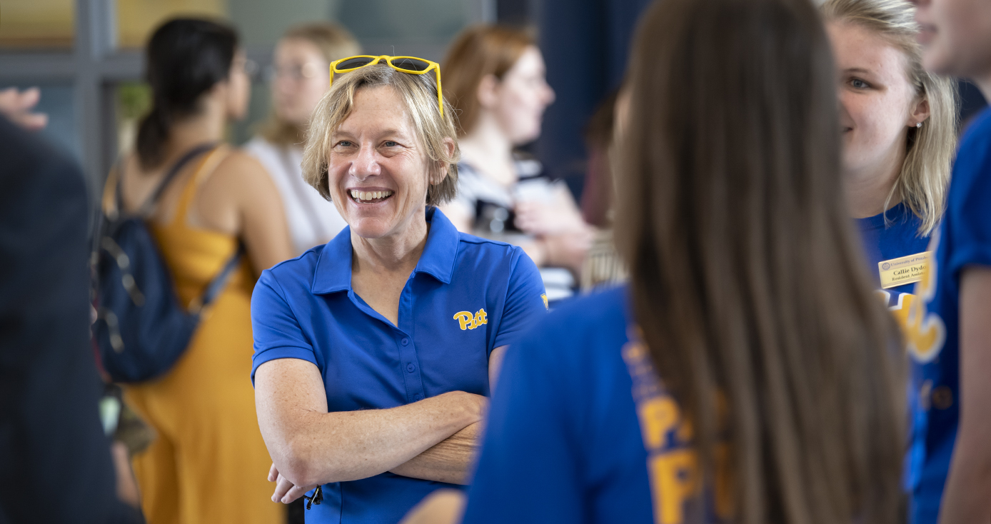 Cudd in a bright blue Pitt collared shirt, talking to students