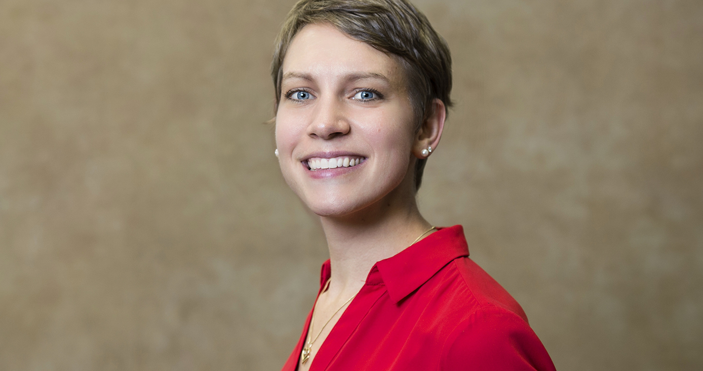 a woman with short blond hair, wearing a red collared shirt