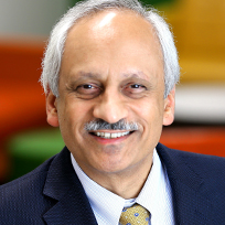 Shekhar in a blue suit, white shirt and gold tie