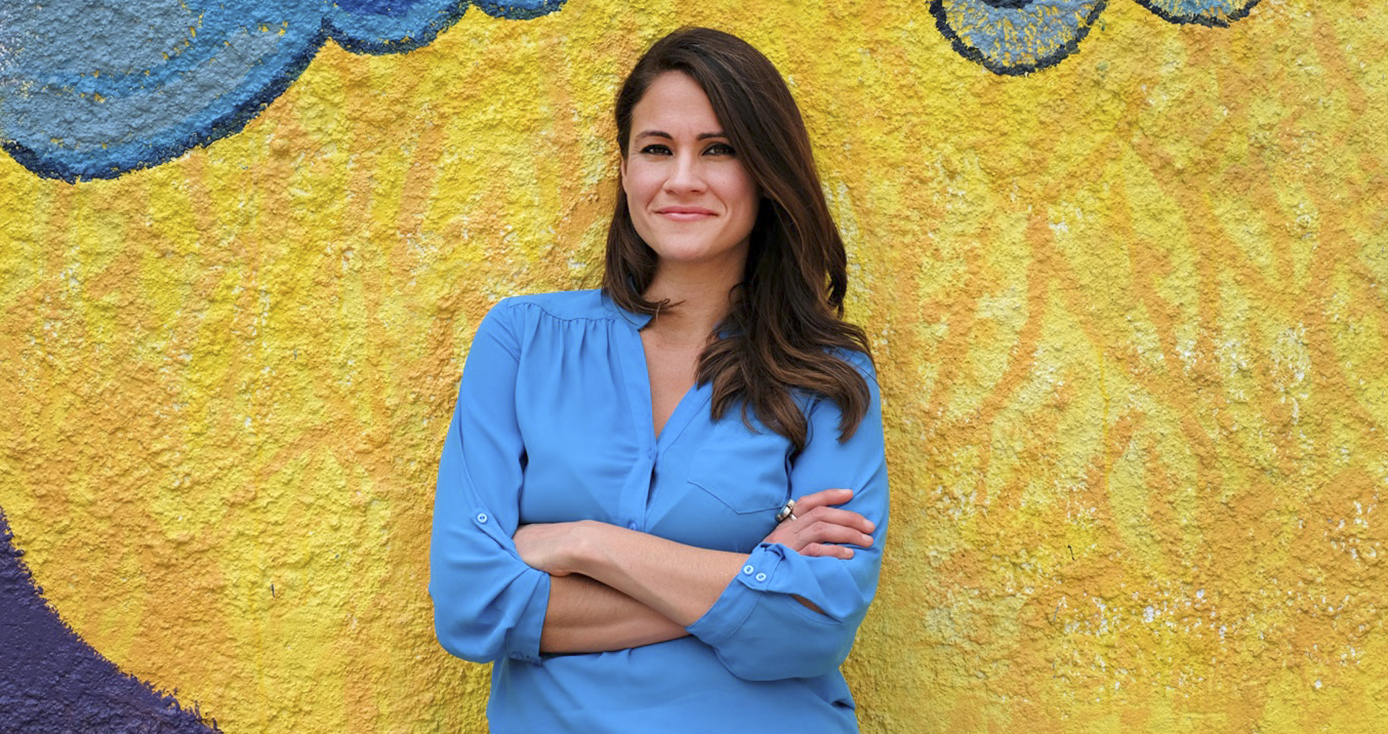 Cruz in a blue shirt in front of a vibrant yellow wall