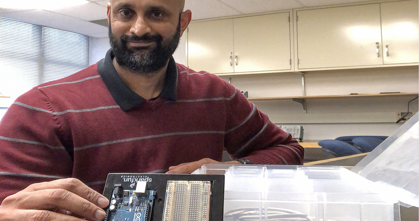 Gurudev Dutt in a red shirt, holding a piece of electronic equipment