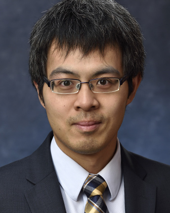 Headshot of Feng Xiong in jacket, tie and white shirt against a dark background.