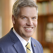 Gallagher in a blue suit and yellow tie