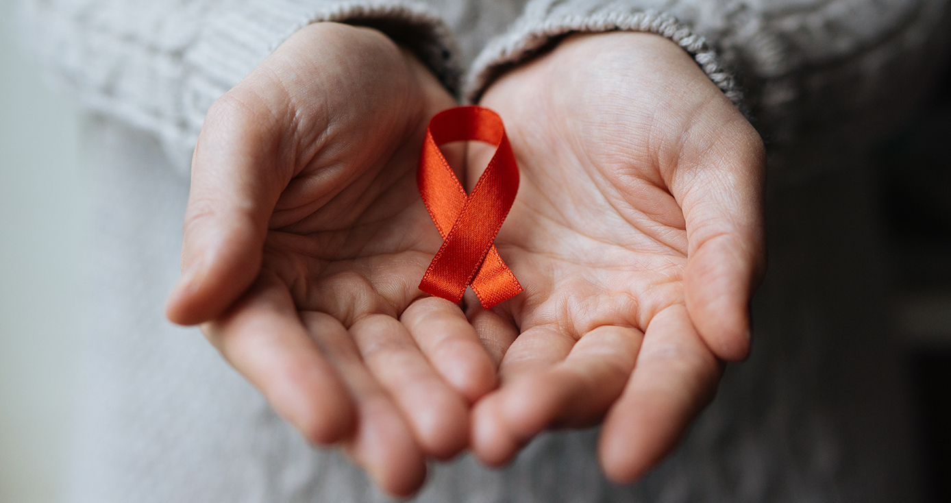 A person in a gray sweater holding a red ribbon in two hands