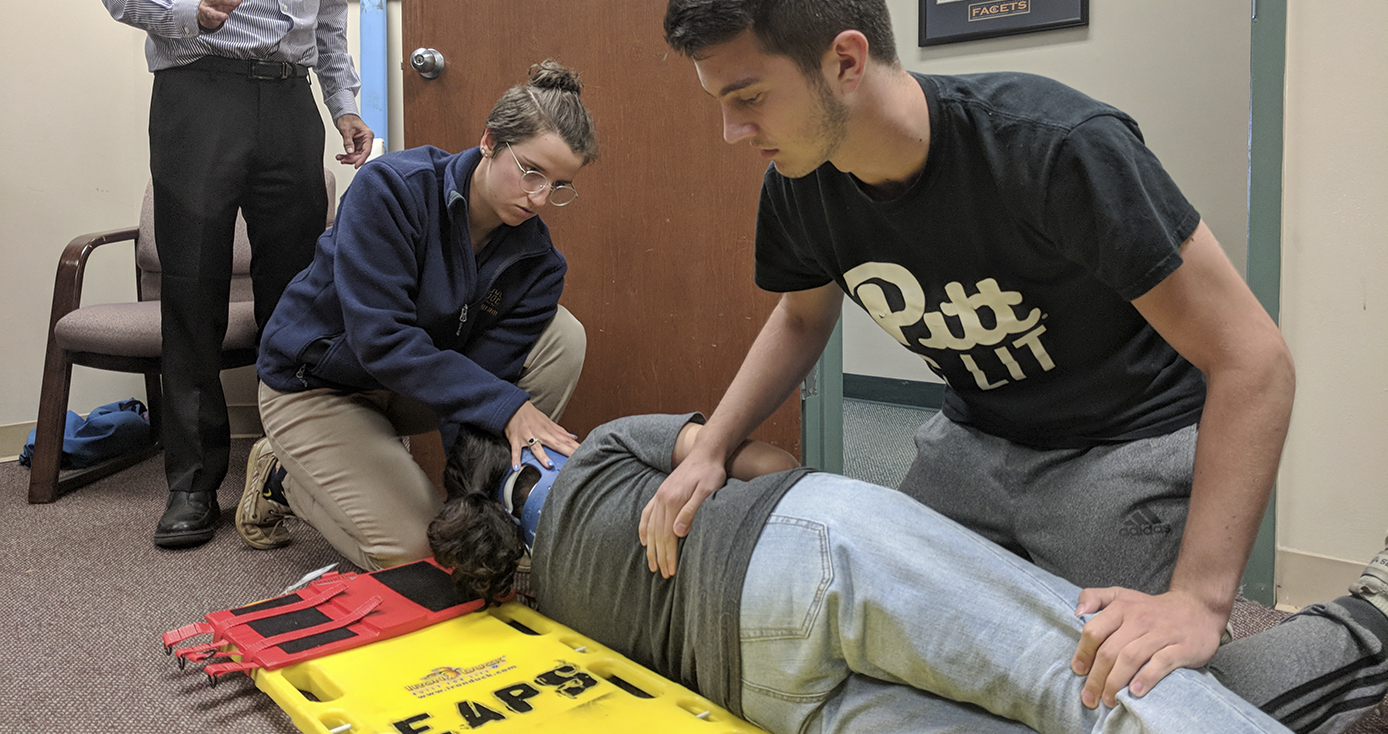 students rolling a person off a stretcher