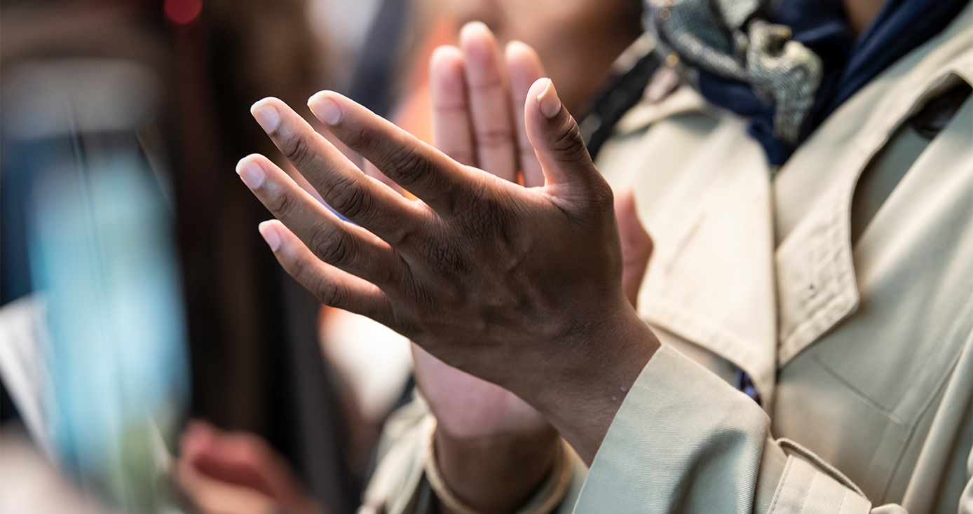 A person in a beige coat clapping