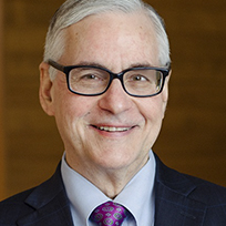 Keeler in a dark suit, blue shirt and red tie