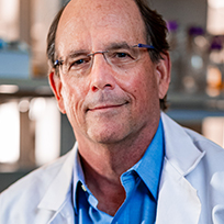 A man in a blue dress shirt and white coat