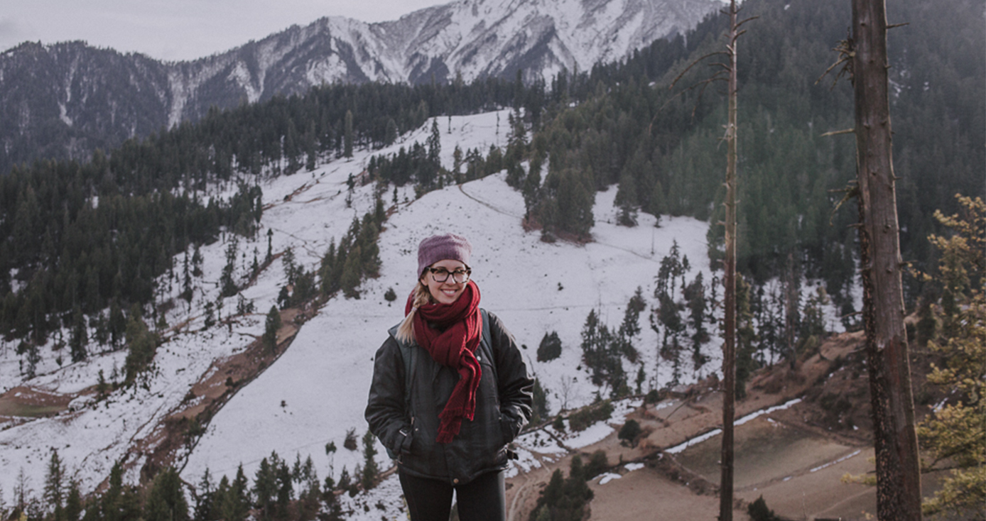 A woman in a coat in front of snowy mountains