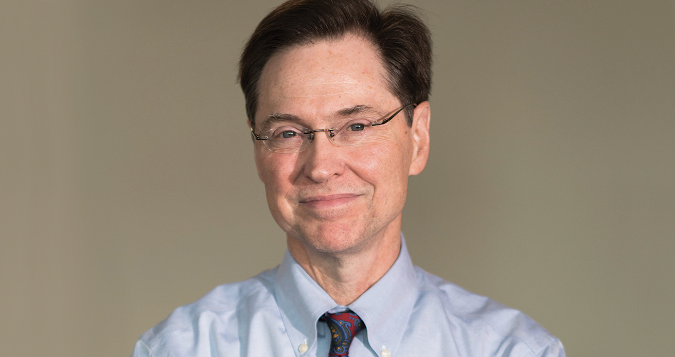 Dermody, a man with dark hair and glasses, in front of a tan background