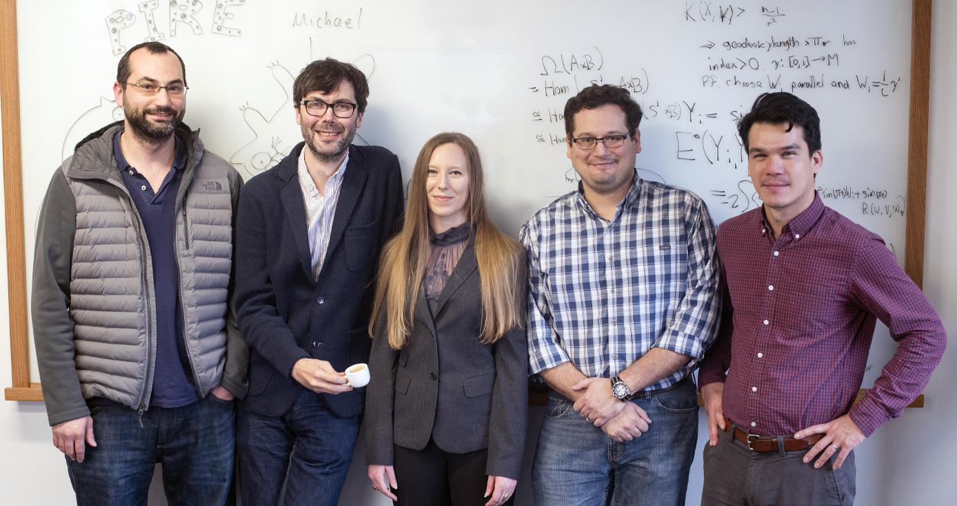 the PIRE team in front of a white board with equations written on it