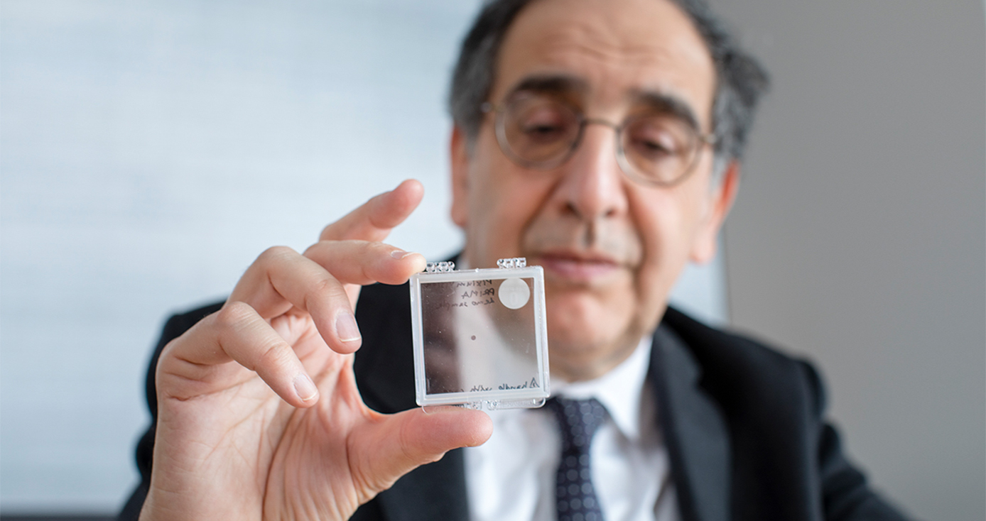 José-Alain Sahel in a black suit and white shirt holding a white square