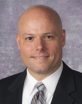 Tillman in front of a light purple background