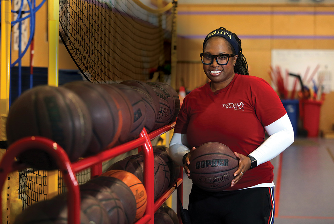 Lauren Wheeler holds a basketball from a rack beside her