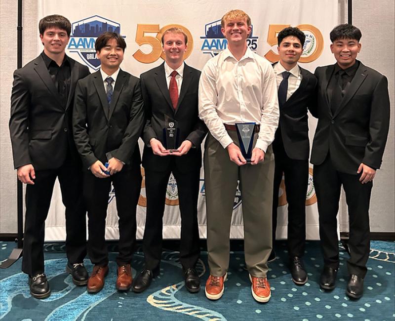 Several nursing students posing in suits with two holding awards