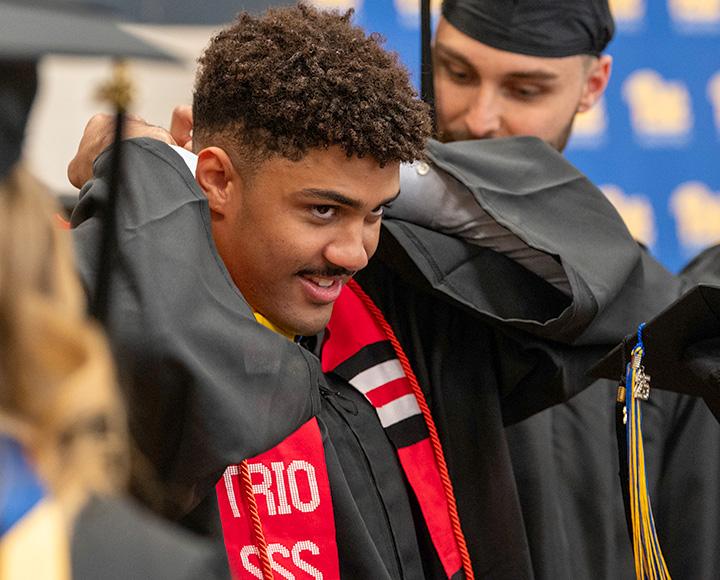 A graduate adjusts their red stole.