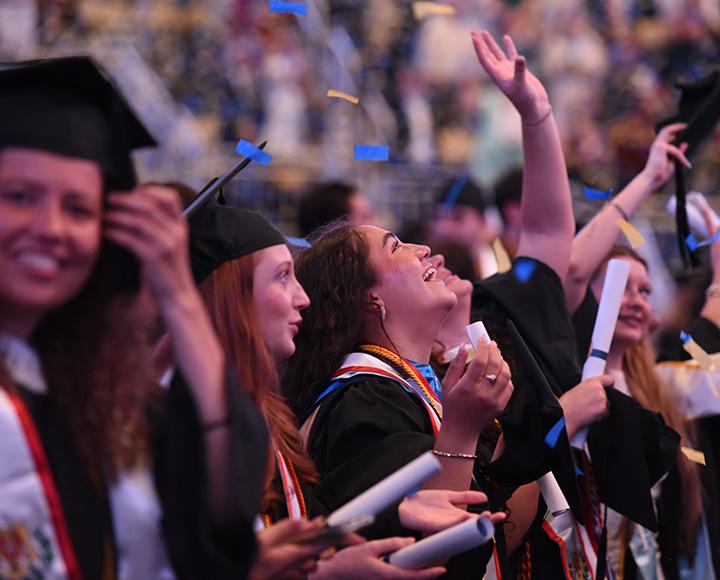 Graduating seniors looking upward at falling confetti