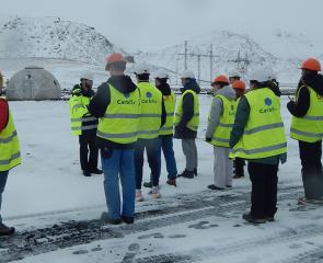 A group of students stand in florescent vests on a snowy plain.