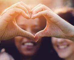 Two people forming a heart shape with their hands