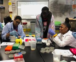 People in tie-dye lab coats work around a black table