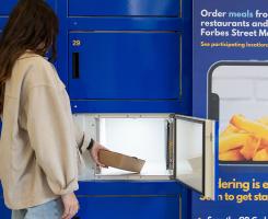 A person takes a to-go container out of a blue food locker