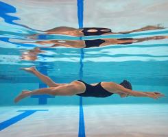 A woman swims underwater in a pool.