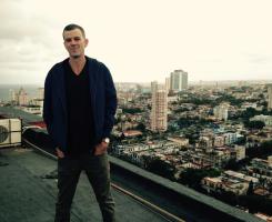 A man stands on a rooftop overlooking the city of Havana.