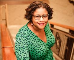 Portrait of Lesha Greene in front of books in Pitt's Fredrick Honors College.