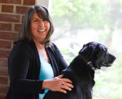 A woman smiles while petting her dog.