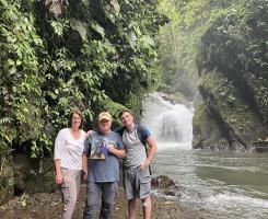 Three people standing in front of a waterfall