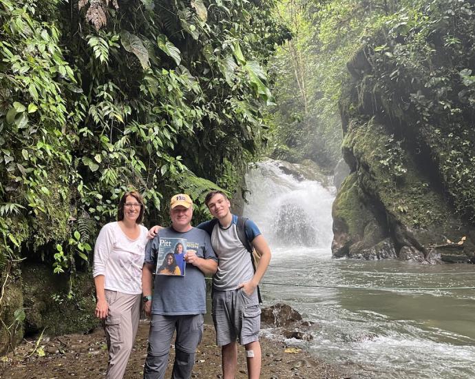 Three people standing in front of a waterfall