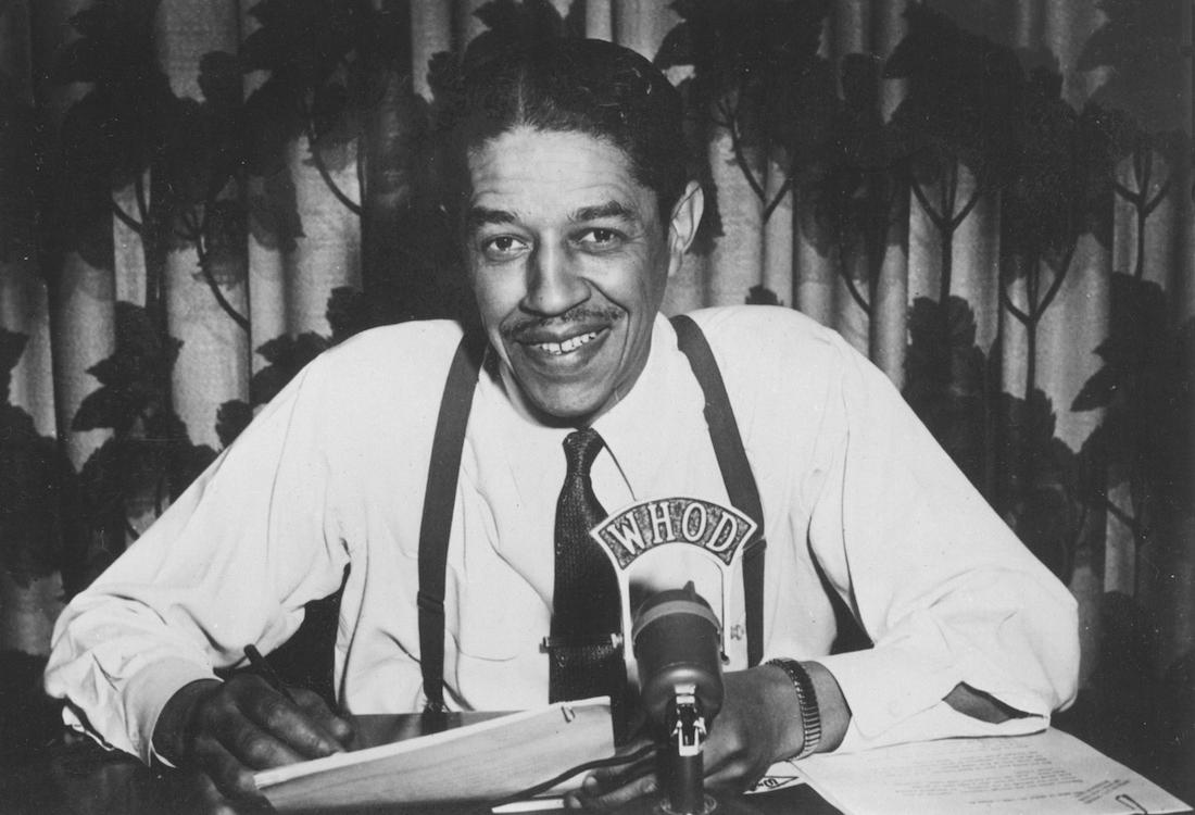 Man sitting at desk behind microphone.