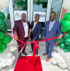 Three people cutting a red ribbon