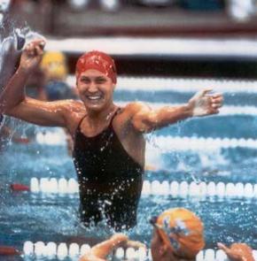 A woman wearing a cap and standing in a pool.