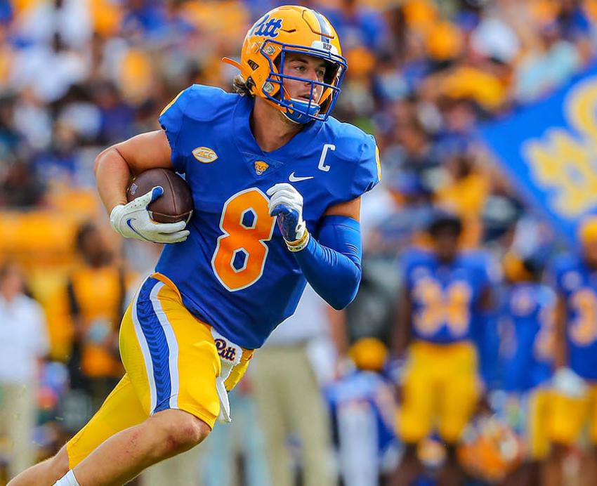 a quarterback in blue and gold with the ball tucked under his arm