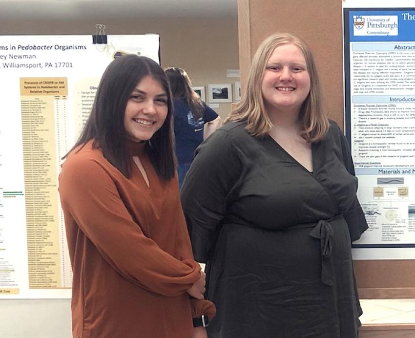 Smiling students in front of a poster