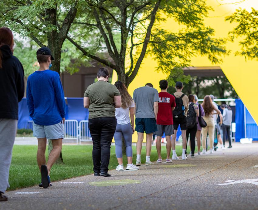 A line of people stand outside