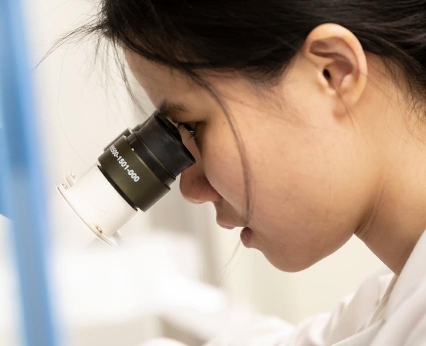 a profile of a scientist looking through a microscope