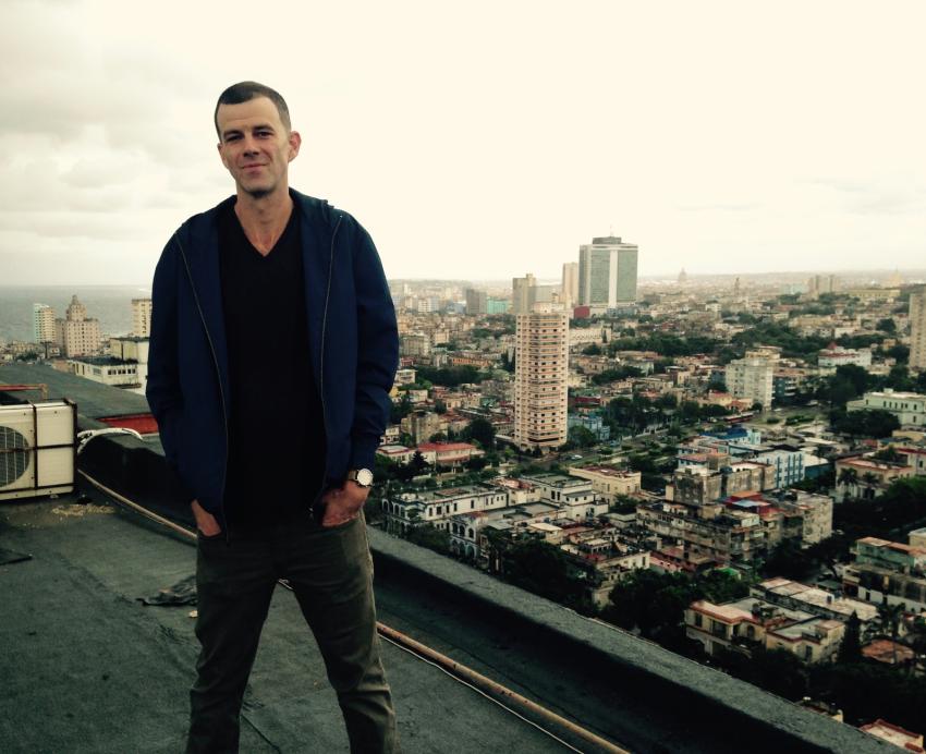 A man stands on a rooftop overlooking the city of Havana.