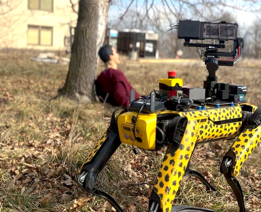 A cheetah-patterned robot outdoors with a test dummy in background