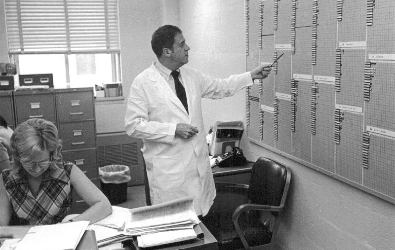 A black and white photo of Fisher pointing a items on a board